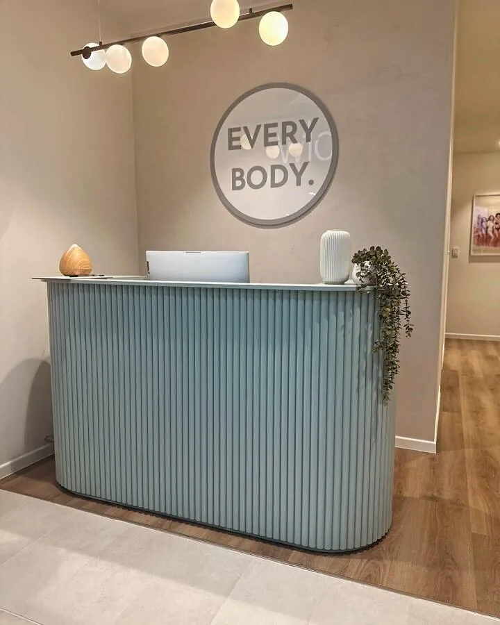 Sage green fluted reception counter below a round logo