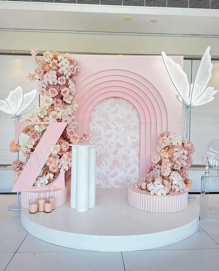 Nested pink and cream arches on a round plinth, dressed with flowers