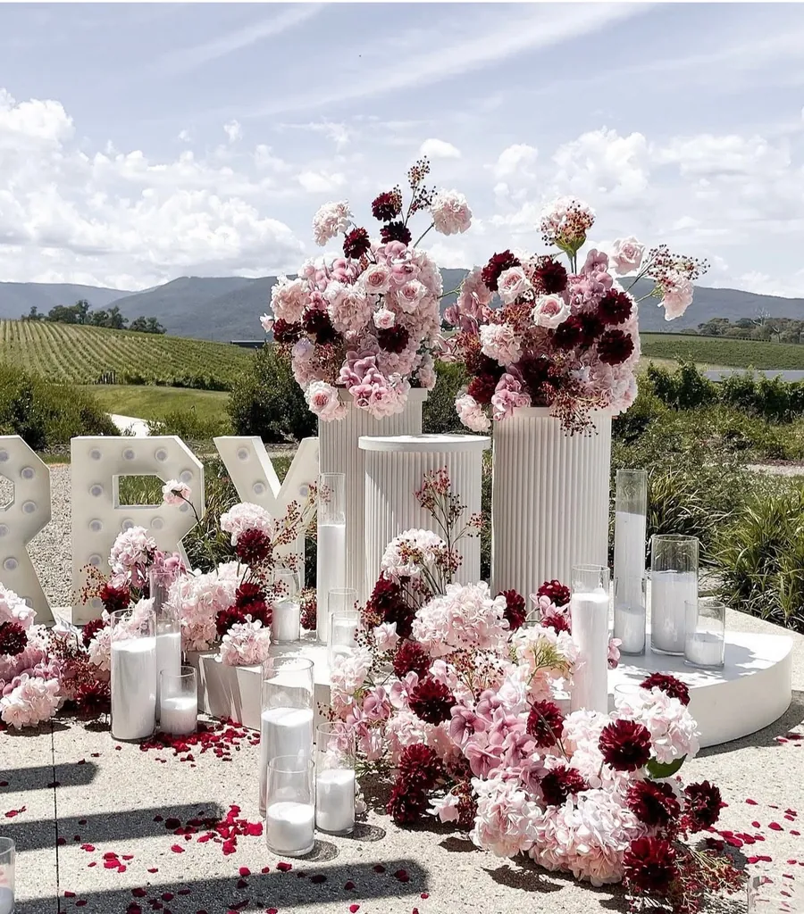 Outdoor event installation with lettering, plinths and florals in a vineyard
