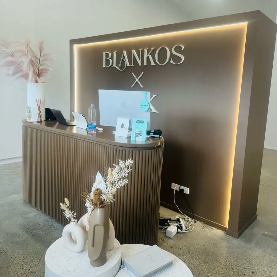 Dark timber-look fluted counter in front of a backlit brand sign