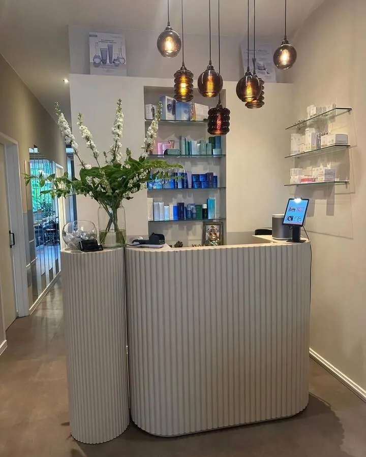 Curved clinic reception counter with coloured glass pendants and wall product display