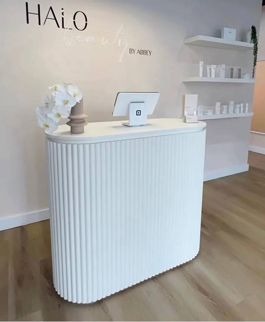 White fluted reception counter in a clinic with product shelving behind