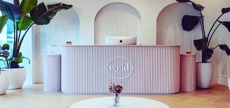 Pink reception counter in front of a run of arched wall niches