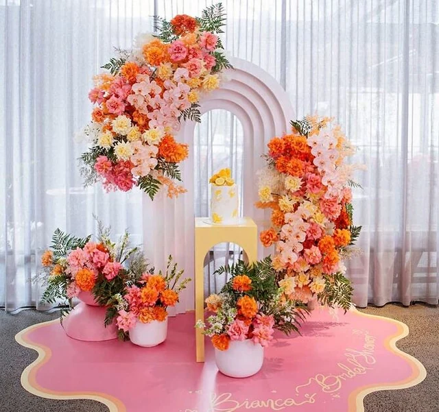 Event set on a pink puddle-shaped plinth with an arch and floral arrangements