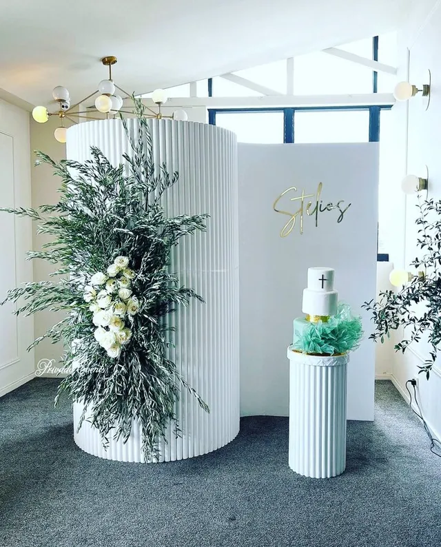 Fluted display plinths and a curved backdrop styled with foliage in a retail space