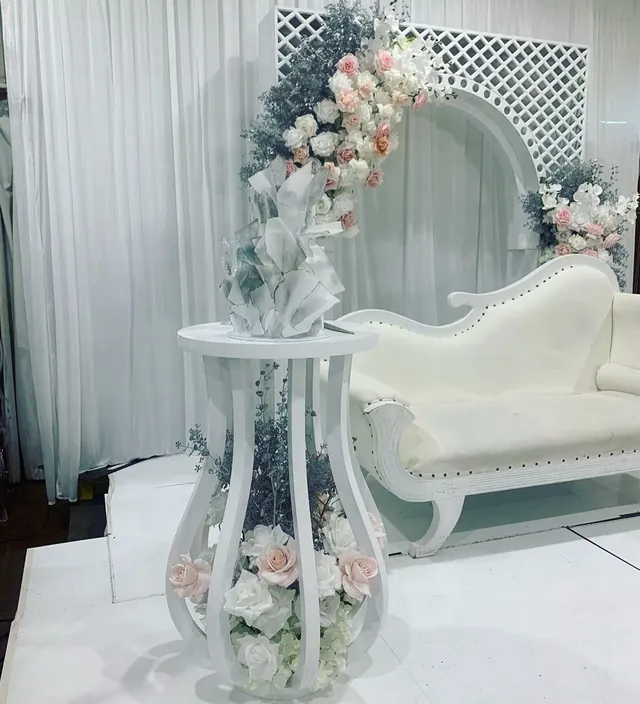 Curved vanity console with a fluted base, styled with florals and drapery