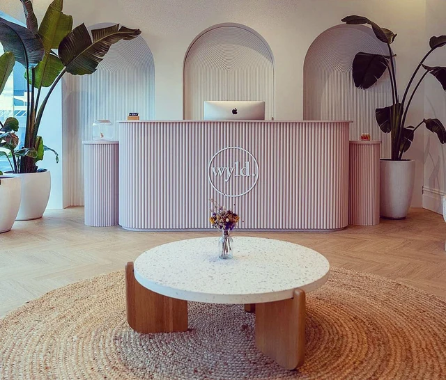 Blush fluted reception counter with matching plinths and arched wall niches behind