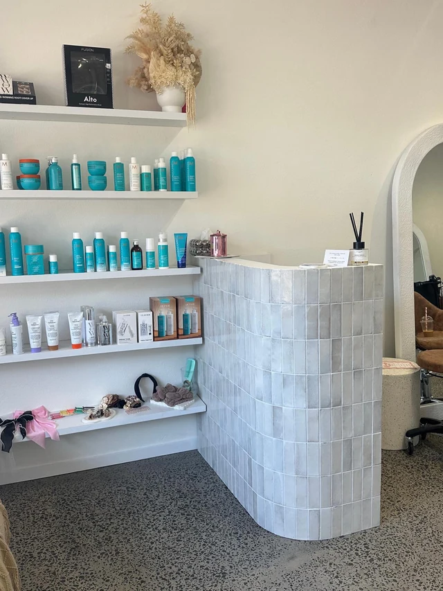 Salon reception counter in a tiled finish with product shelving alongside
