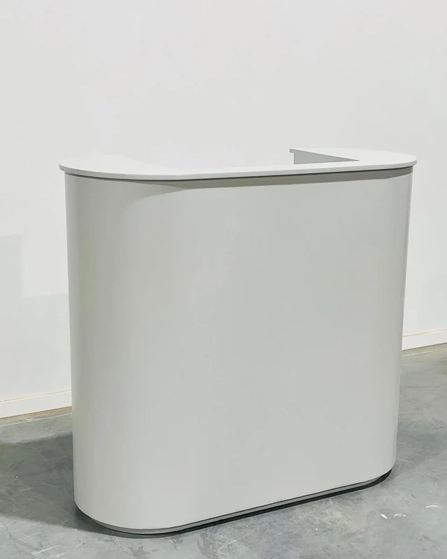 Cream reception desk with a smooth curved front, photographed from the return end