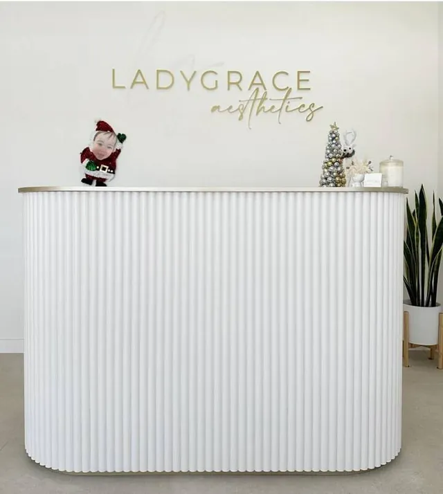 White fluted reception counter below aesthetics clinic signage