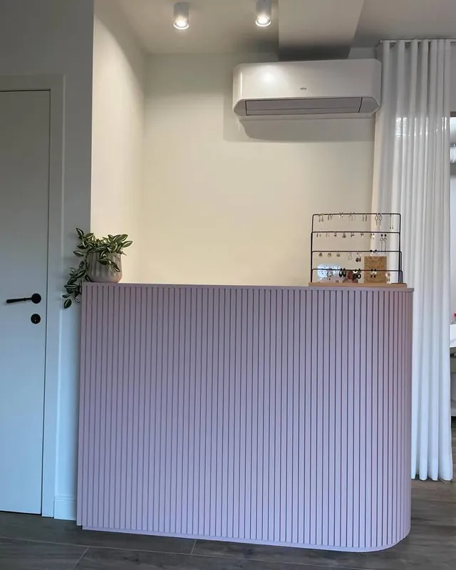 Lilac fluted reception counter installed in a studio with a white door alongside