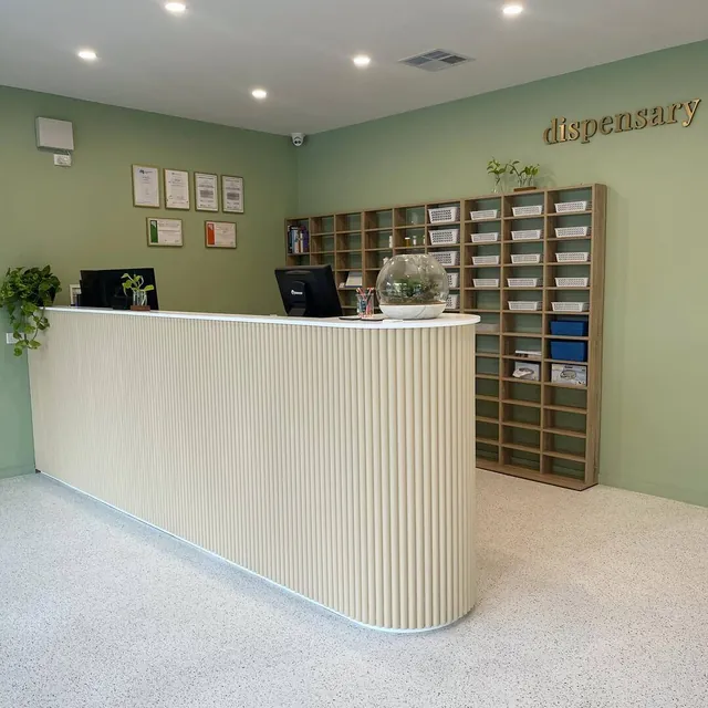 White fluted counter in a dispensary with green walls and pigeonhole shelving