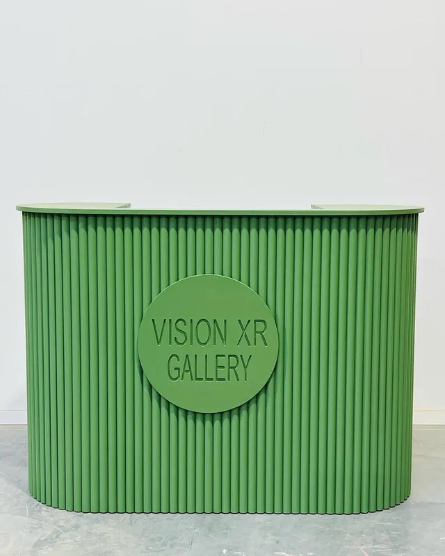 Green fluted reception counter with a round gallery logo on the front