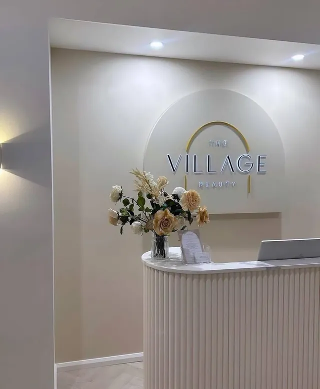 White curved reception counter beneath a backlit arched logo